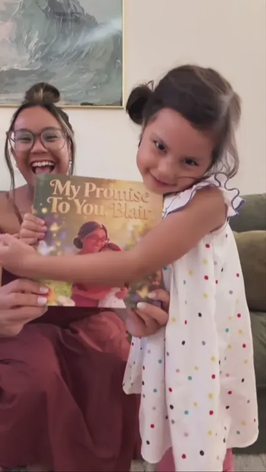 A smiling daughter holds her personalised book beside her mum