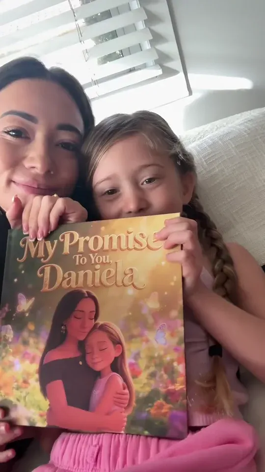 A mum and daughter cuddle together behind their personalised book cover